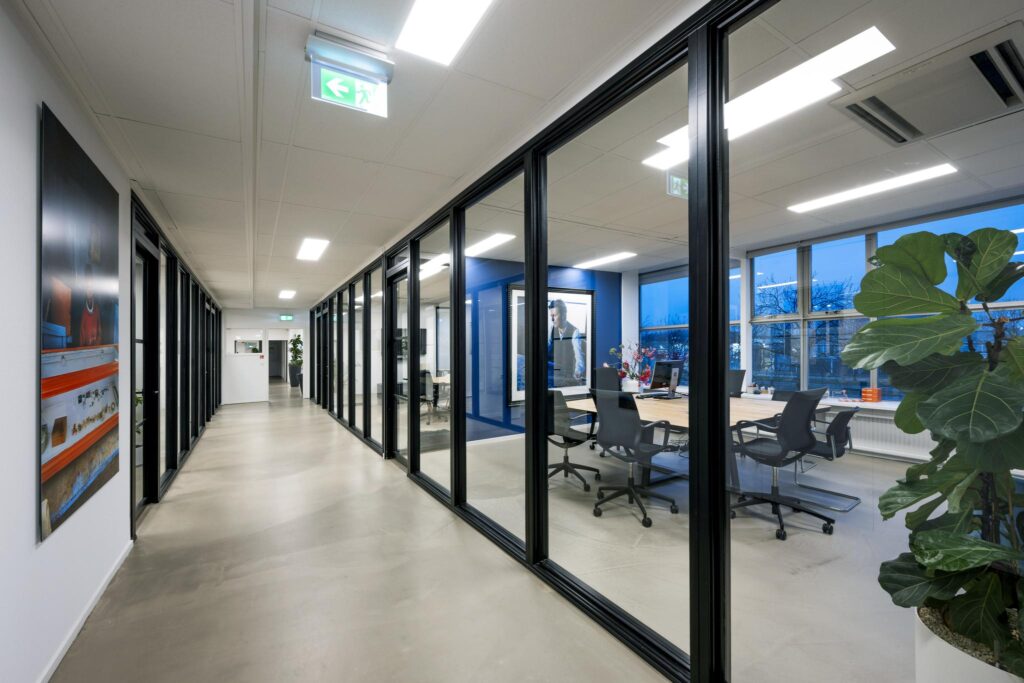 Moderne kantoorruimte aan de Van der Madeweg met glazen wanden, bureaus en vergaderruimte.